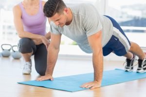Trainer assisting man with push ups